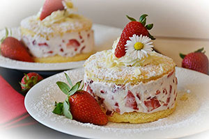 Strawberry-flavoured cakes with cream and fruit topping
